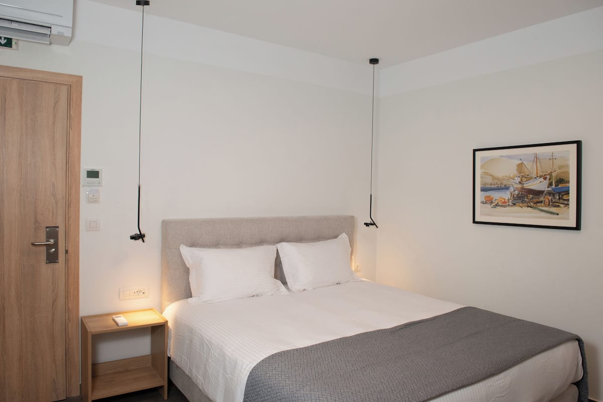 A neatly arranged hotel room with a bed, bedside table, and a painting on the wall.