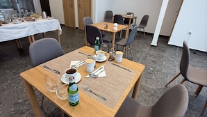 Un espace repas avec des tables dressées pour le service, des chaises et une bouteille de bière.
