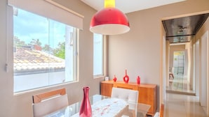 A modern dining area with a glass table, white chairs, and a red pendant light. - Modern Apartment 1km From Ondina Beach Slo0301 (Salvador)