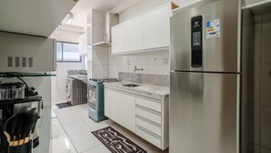 Une cuisine moderne avec des armoires blanches, un réfrigérateur en acier inoxydable, un four encastré et une cuisinière à gaz.