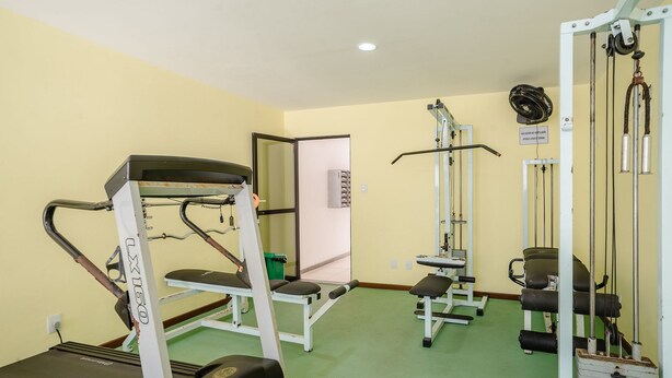 Une salle de sport équipée de divers appareils d’entraînement, notamment un support à squats, un banc de développé couché et une machine à câbles.