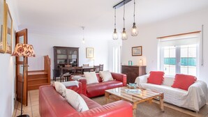Una sala de estar con sofás de cuero rojo, una mesa de centro de madera, y un comedor con un aparador y una mesa de madera.