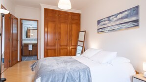 Un dormitorio con una cama grande, un armario de madera y un cuadro de un paisaje marino.