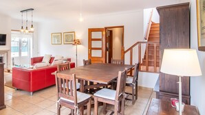 Un comedor con una mesa y sillas de madera, un sofá rojo y una escalera que sube a un piso superior.