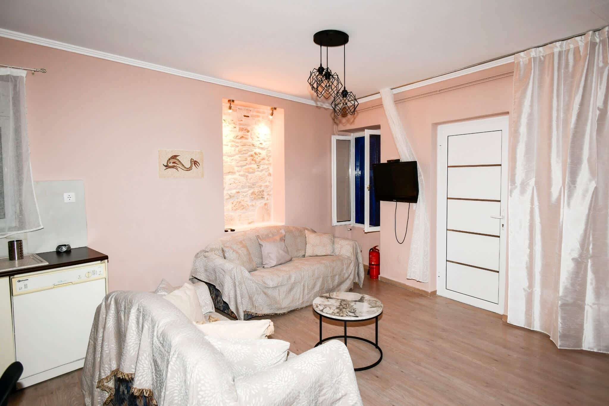 A living room with a sofa, a small round table, a television, and a stone wall accent.