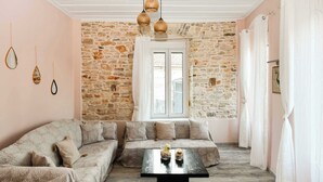 Un salón acogedor con pared de piedra, un ventanal grande y una mesa baja negra.