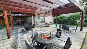 An outdoor patio area with tables and chairs, a pergola structure, and a view of the surrounding garden. - Nui Supreme Beach Living  (Ipojuca)