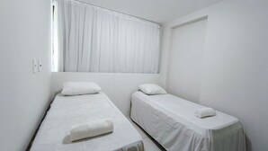 A twin room with two single beds, a window with curtains, and a door. - Nui Supreme Beach Living  (Ipojuca)