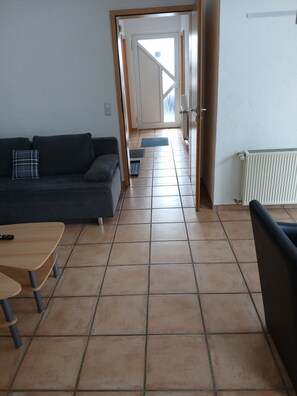 Een woonkamer met een bank, een salontafel en een deur naar een balkon.