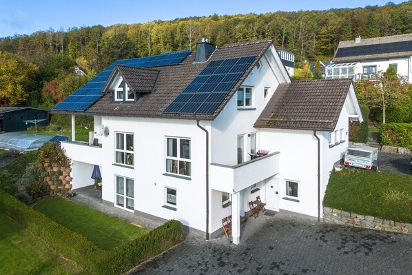 A two-story house with solar panels on the roof, a garage, and a well-maintained lawn.