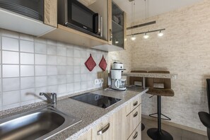 A modern kitchen with a stainless steel sink, a built-in microwave, and a coffee maker.