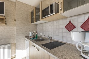 A kitchen with a granite countertop, stainless steel sink, and a microwave above it.