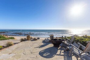 A stone pathway leading to beach chairs and potted plants overlooking the ocean. - Casa Azul by Oraklus (Malibu)