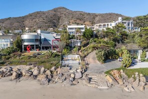 A coastal residential area with modern houses, a rocky beach, and a mountain in the background. - Casa Azul by Oraklus (Malibu)