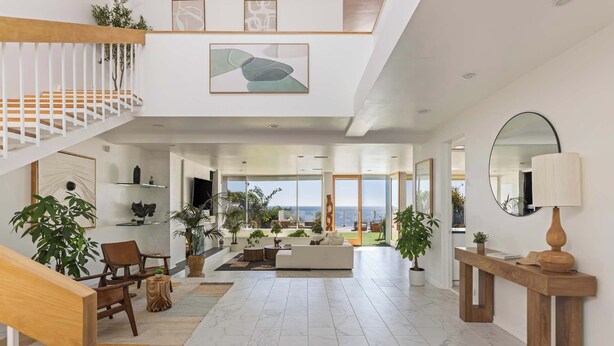 Un amplio salón con escaleras, asientos y vistas al exterior.