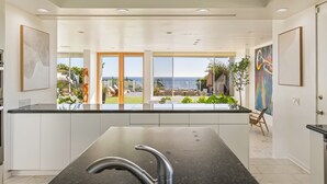 Una cocina moderna con una isla grande, vistas al exterior y un comedor con sillas y una mesa.