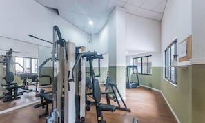 A gym with various exercise machines, a mirror, and a window.