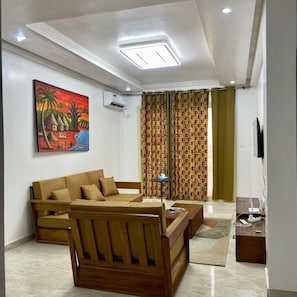 A living room with a sofa, a coffee table, a TV, and a painting on the wall.