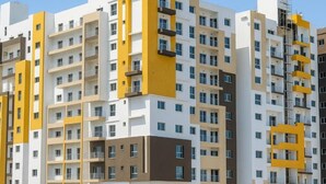 Um edifício residencial com várias andares, varandas, design arquitetônico moderno e céu claro.