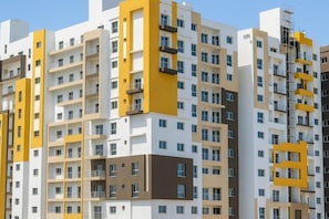 A multi-story residential building with balconies, a modern architectural design, and a clear sky.