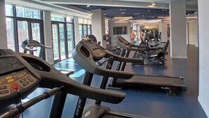 A gym with treadmills, exercise bikes, and a large window providing natural light. - Luxury 2 Bedrooms appartment near CN tour (Toronto)