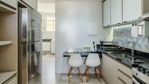 Eine moderne Küche mit Edelstahlgeräten, weißen Schränken und einer gefliesten Spritzschutzwand.