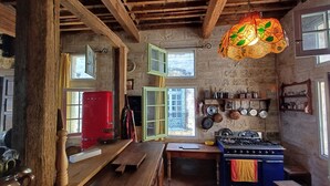 A rustic kitchen with wooden beams, a red refrigerator, hanging pots, and a gas stove. - House, gîte, apartment, private mansion with character historic center Pézenas (Pézenas)