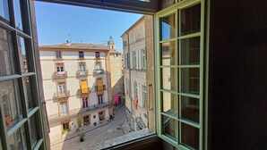 A view from a window overlooking a narrow street with buildings featuring balconies and ground-floor shops. - House, gîte, apartment, private mansion with character historic center Pézenas (Pézenas)