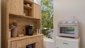 Cuina amb armaris de fusta, una cafetera i un forn blanc.