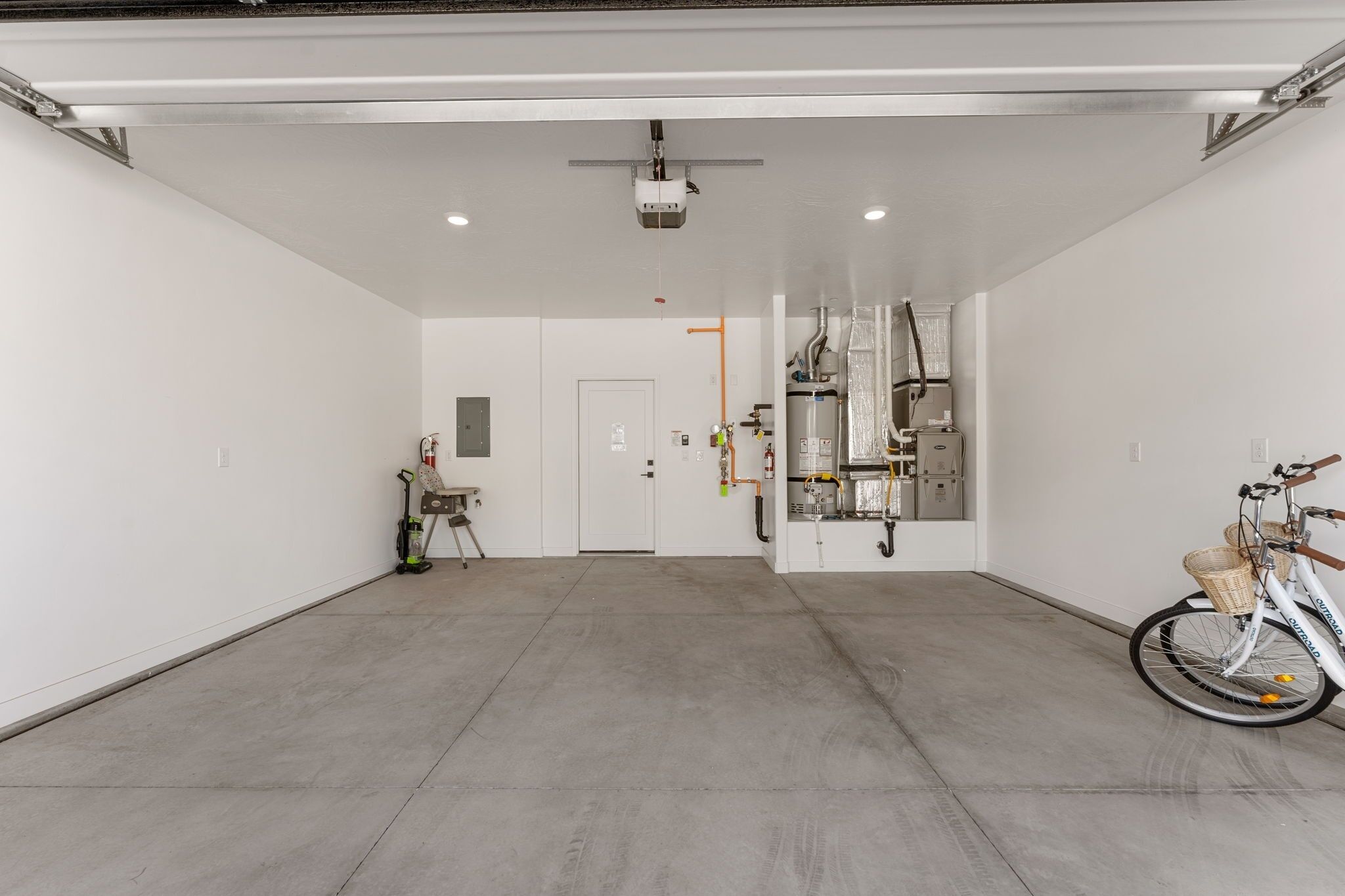 A spacious, well-lit indoor area with a concrete floor, a ceiling-mounted projector, and a bicycle parked on the right.