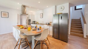 A modern kitchen with a dining area, stainless steel appliances, and a staircase leading to another level. - VILLA SON TONI (Crestatx)