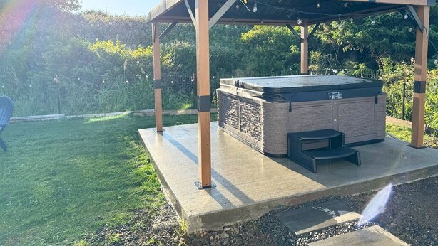 Un jacuzzi bajo una pérgola de madera en un jardín.