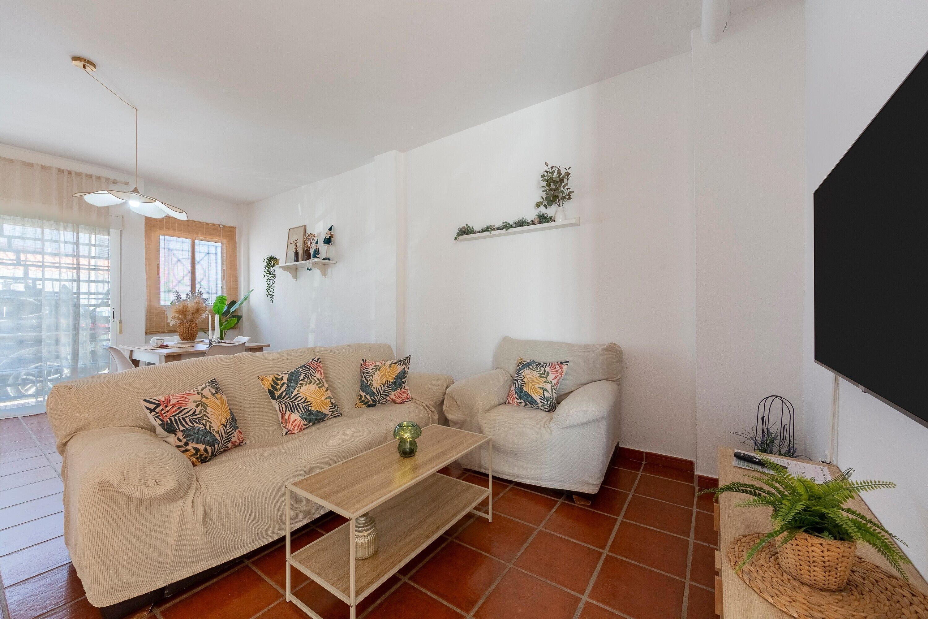 Una sala de estar con sofá, mesa de centro y plantas decorativas.