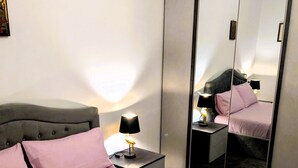 Un dormitorio con cama, mesitas de noche, un espejo y un armario.