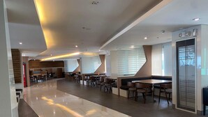 A spacious, modern hotel lobby with a long, polished tile floor, multiple seating areas with tables and chairs, and large windows allowing natural light. - Green Residences Taft Ave. by darpm (Manila)