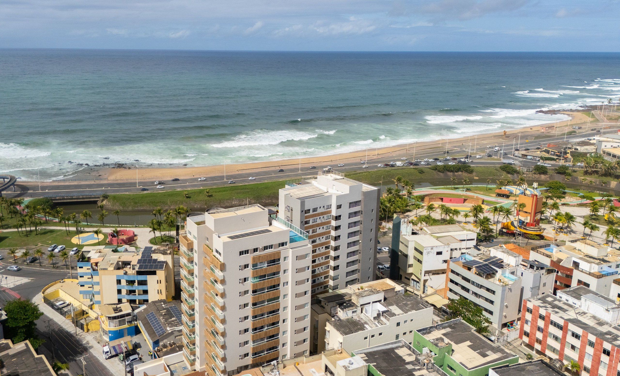 Un paisaje urbano costero con rascacielos, una playa y una autopista.