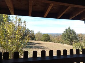 A wooden deck with a view of a grassy field and trees.