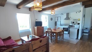A cozy room with a wooden bench, a table, and a kitchen area with a stove and cabinets. - Vacation rental in the middle of the Viaur Gorges (Pampelonne)