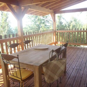 An outdoor wooden deck with a table and chairs, surrounded by a wooden fence. - Vacation rental in the middle of the Viaur Gorges (Pampelonne)