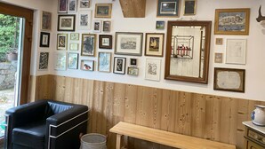 A room with wooden paneling, a black leather chair, a wooden bench, and a wall adorned with various framed artworks. - Chalet "Les Pommes de Pin", sleeps 10-12, 8 rooms, with terrace and garden (La Bresse)