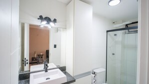 Ein Badezimmer mit großem Spiegel, zwei Waschbecken, einer Dusche und einer Toilette.