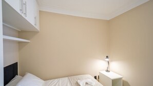 Ein Schlafzimmer mit einem Bett, einem Nachttisch mit Lampe und einem weißen Kleiderschrank.