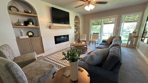Un salon comprenant un canapé, des fauteuils, une table basse, un téléviseur et un ventilateur de plafond.