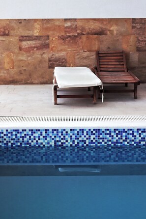 Una piscina al aire libre de temporada, sombrillas, tumbonas