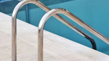 Una piscina al aire libre de temporada, sombrillas, tumbonas