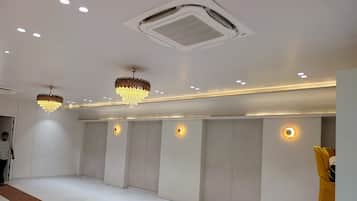 Una habitación amplia con alfombra blanca, iluminación empotrada y un equipo de aire acondicionado grande en el techo.