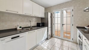 A modern kitchen with white cabinets, a stainless steel sink, a microwave, and a refrigerator.