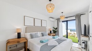 A hotel room with a bed, bedside tables, a TV, and a balcony with a view.