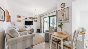 A modern living room with a sofa, TV, and dining area. - Apt. Casa Coco - Aura Villas (Playa Blanca)