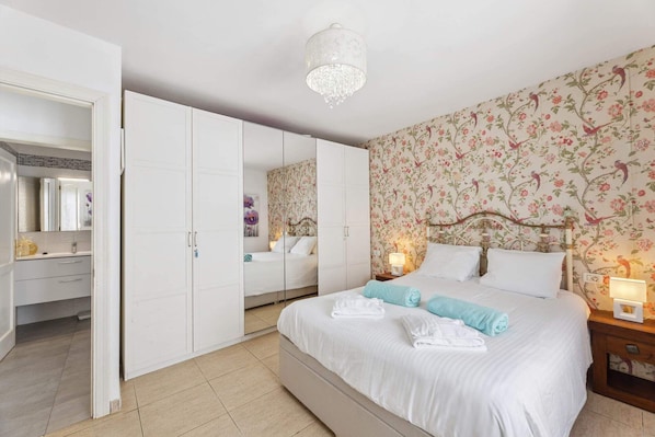 Un dormitorio con una cama grande, un armario, un espejo y papel tapiz floral.